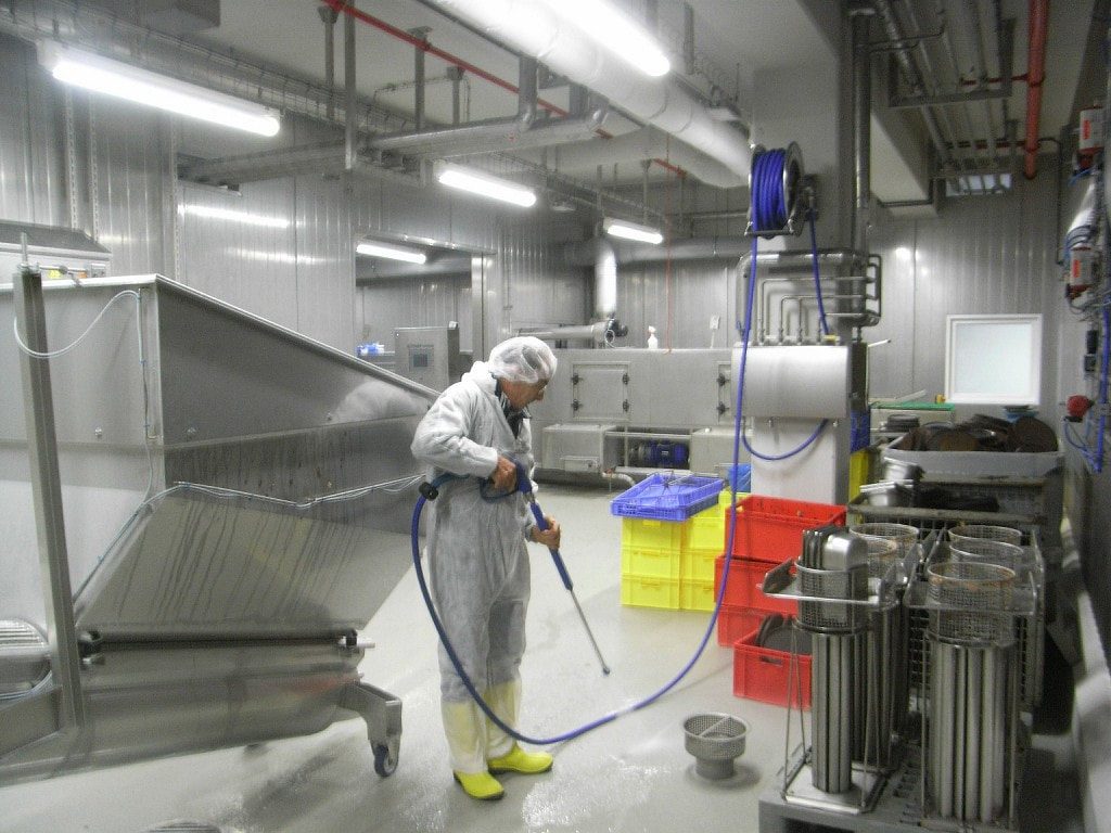 Limpieza técnica industrial — técnico con equipo de alta presión en planta de producción