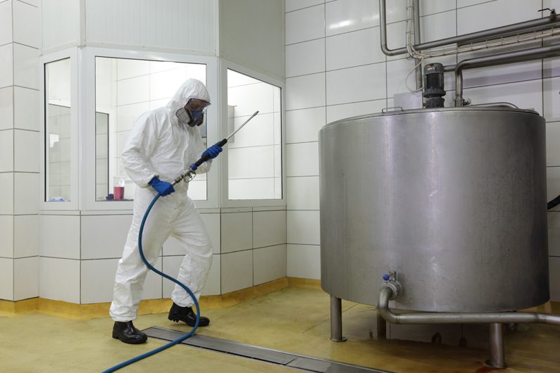 Técnico R&B realizando saneamiento de instalaciones industriales con equipo de protección completo